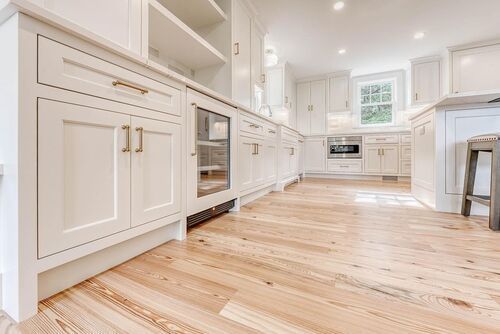 A kitchen with white cabinets and hardwood floors.