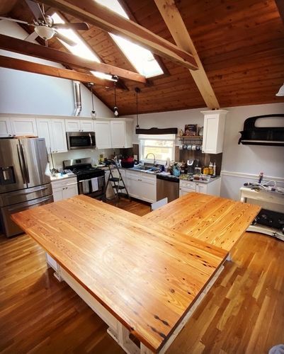 There is a large wooden table in the middle of the kitchen.