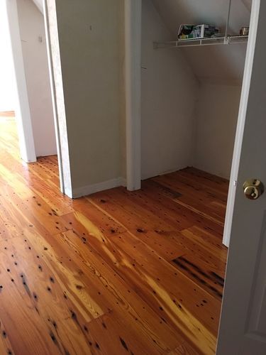 A room with hardwood floors and a closet with a shelf.