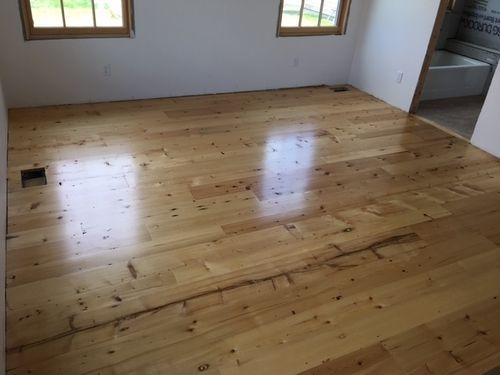 A bedroom with hardwood floors and two windows.