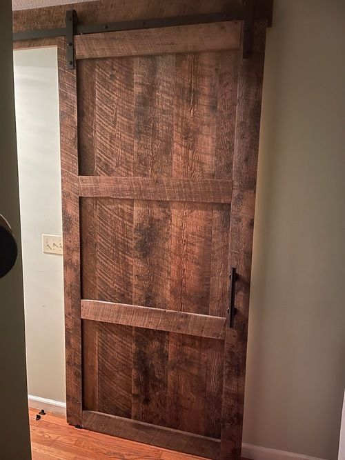 A wooden sliding barn door is in a hallway.