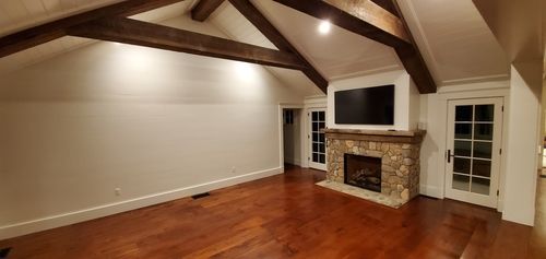 A living room with hardwood floors , a fireplace and a flat screen tv.