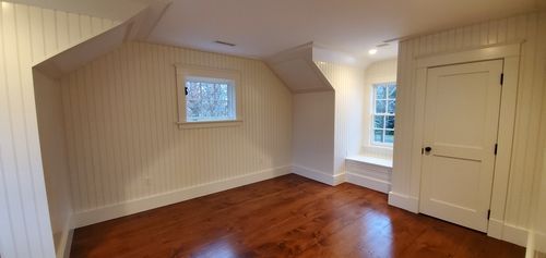 An empty room with hardwood floors , white walls and a window.