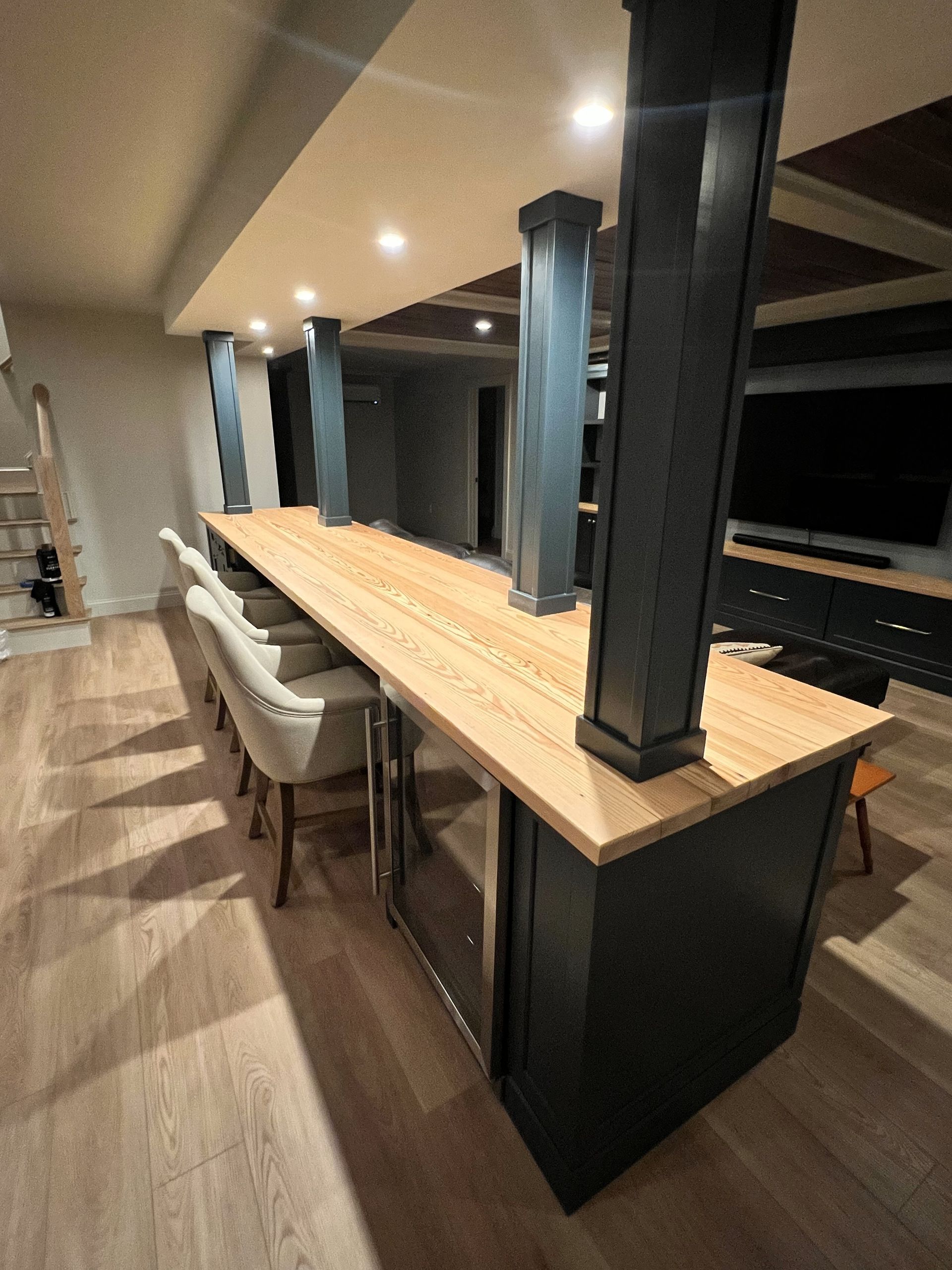 A kitchen with a long wooden counter top and chairs.