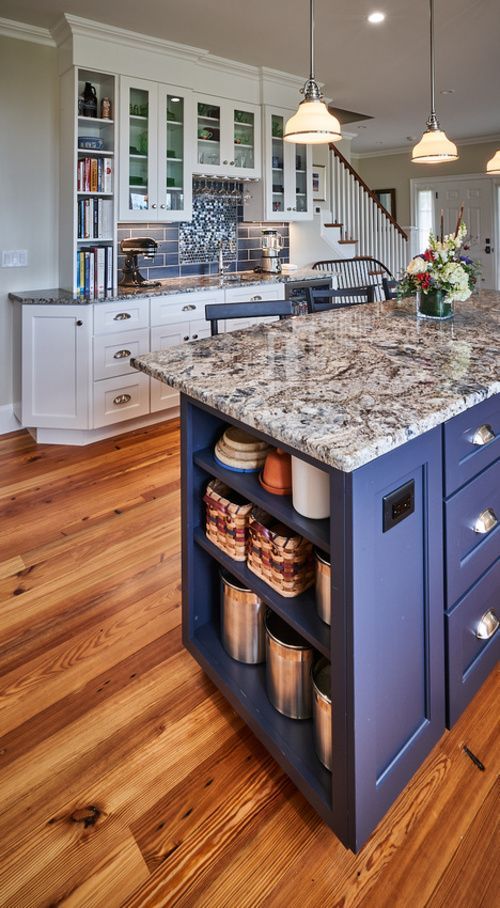 A kitchen with a blue island and a granite counter top.