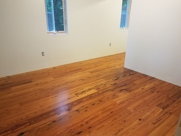 A bedroom with wooden floors and white walls.