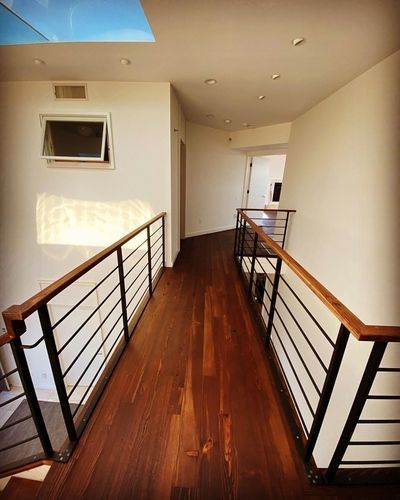 A hallway with a wooden floor and a black railing