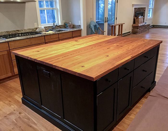 A kitchen island with a wooden top and black cabinets