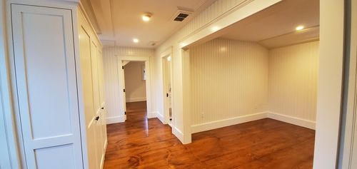 An empty room with hardwood floors and white walls in a house.