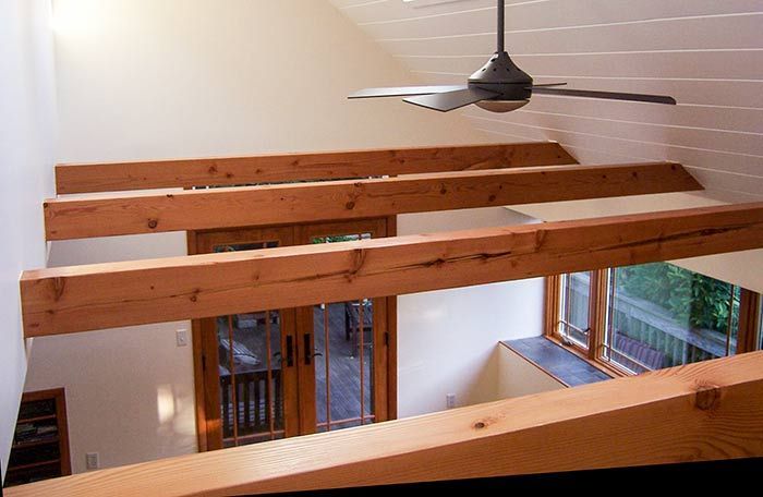 A ceiling fan is hanging from the ceiling of a room with wooden beams.