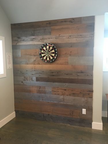 A dart board is hanging on a wooden wall.