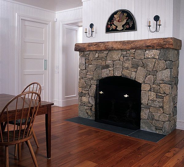 A stone fireplace in a room with a table and chairs