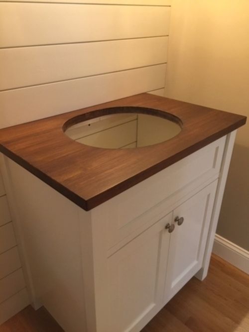 A bathroom vanity with a wooden counter top and a sink.