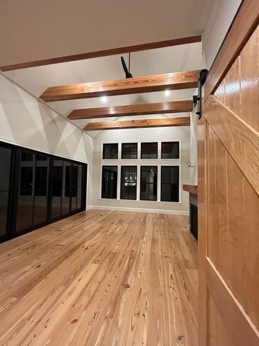 A large empty room with hardwood floors and wooden beams.