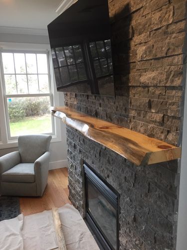 A living room with a fireplace , chair , and television.