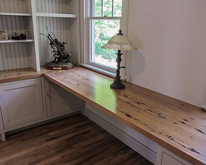 A lamp sits on a wooden desk in front of a window