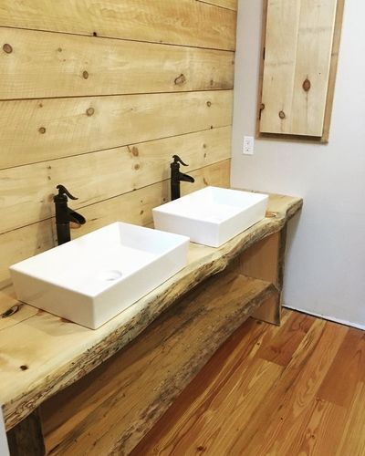 Two sinks are sitting on a wooden counter in a bathroom.