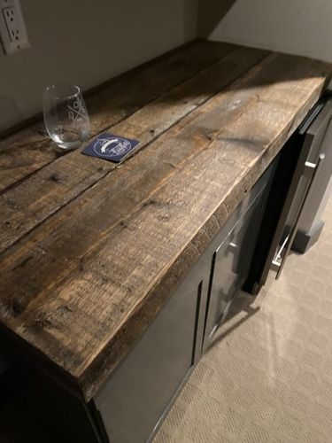 A wooden counter top with a glass and a coaster on it.