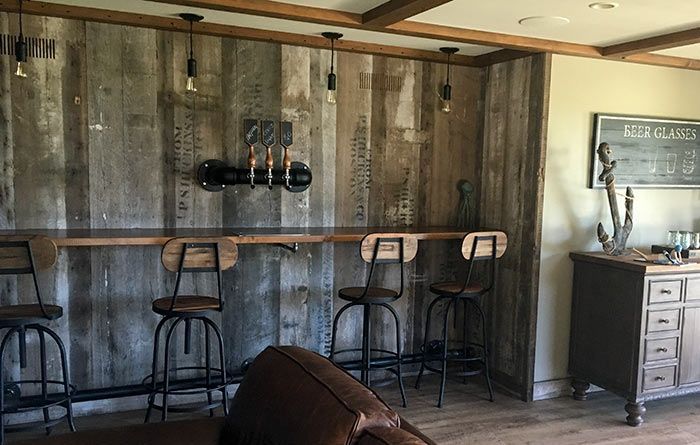 A living room with a bar and stools and a couch.