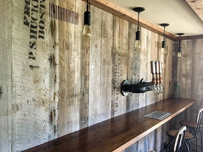 A wooden bar with a bottle holder on the wall.