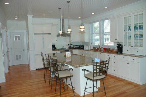 A kitchen with white cabinets , granite counter tops , and a large island.