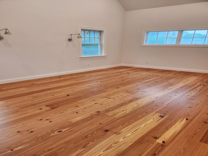 An empty room with hardwood floors and two windows.