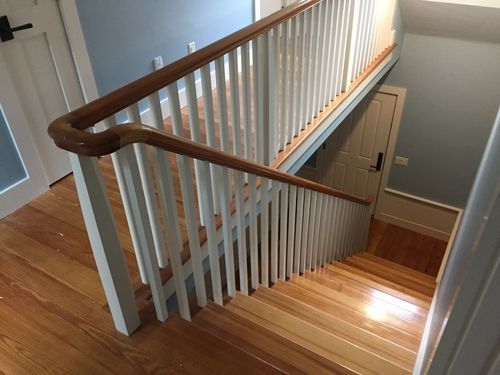 A wooden staircase with a white railing and a wooden handrail.