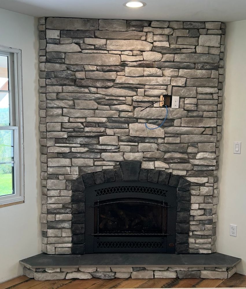 Stone fireplace surround with a black wood stove insert in a living room.