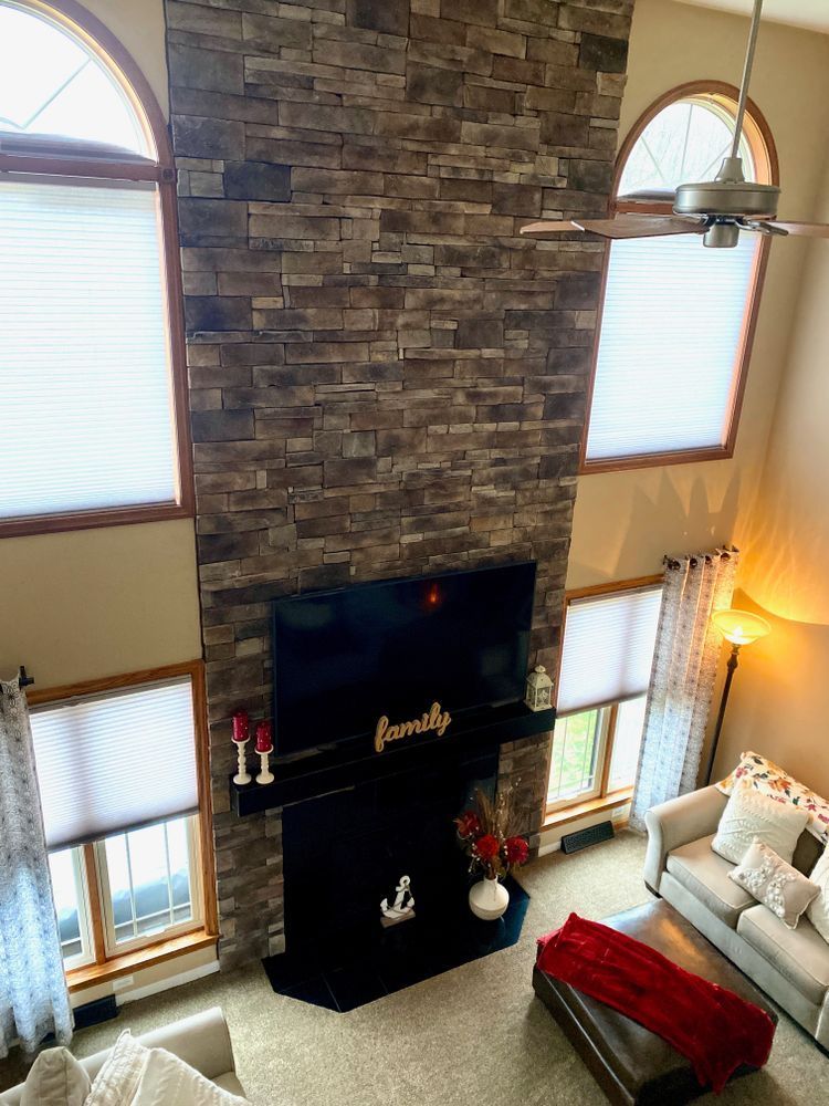 Tall stone fireplace in a bright living room with arched windows, candles, and red bench seating.
