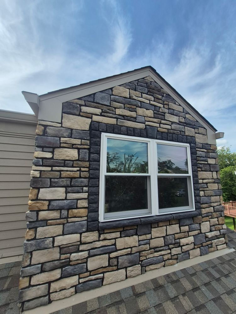 Stone-faced dormer with a double window beneath a blue sky and roof shingles