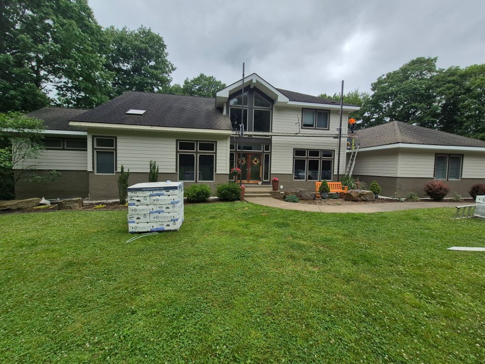 Two-story house with a lawn and flower beds, with a sign in the front yard.