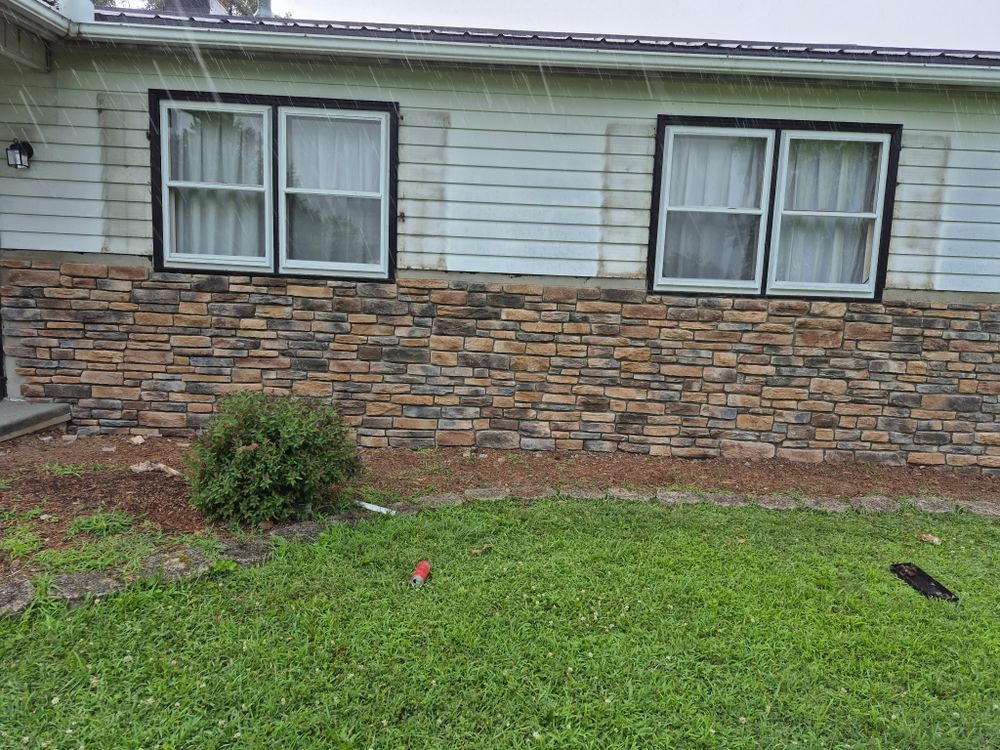 House exterior with stone lower facade, white siding, two windows, and a grassy front yard.