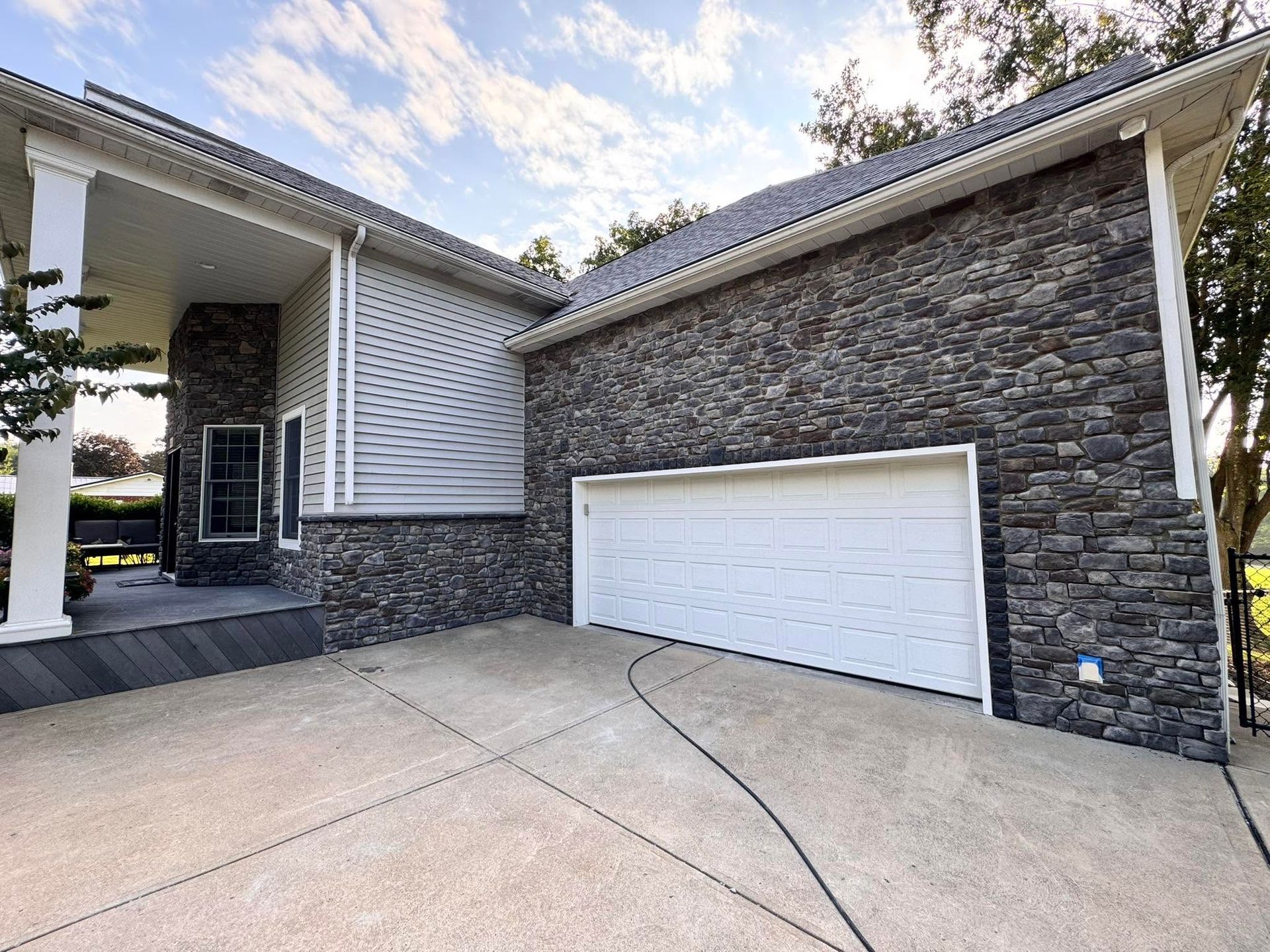 Modern house exterior with stone garage, white trim, and a concrete driveway