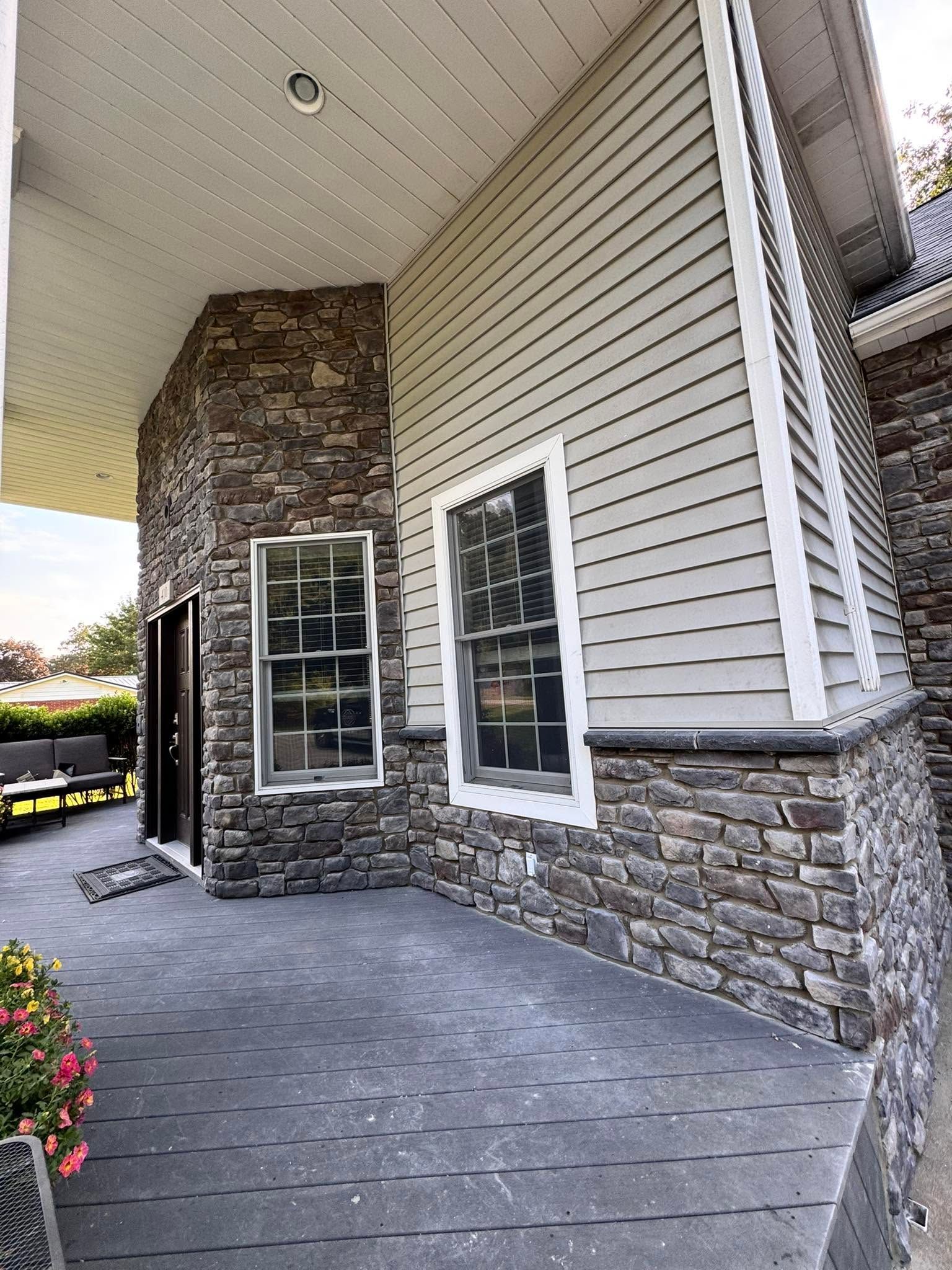 Stone and siding house entrance with covered porch and paved walkway