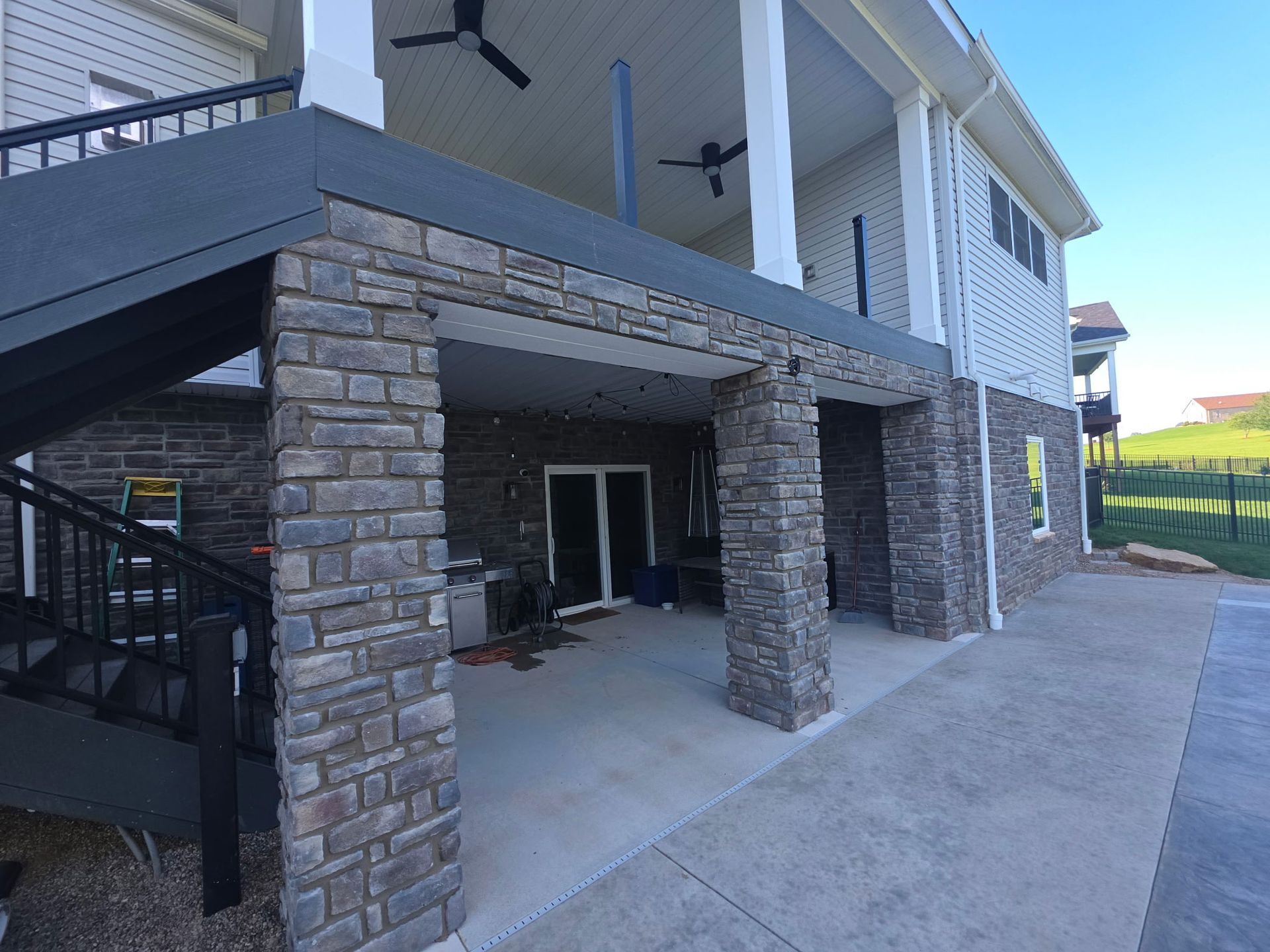 Stone-walled building exterior with covered patio, stairs, and concrete walkway