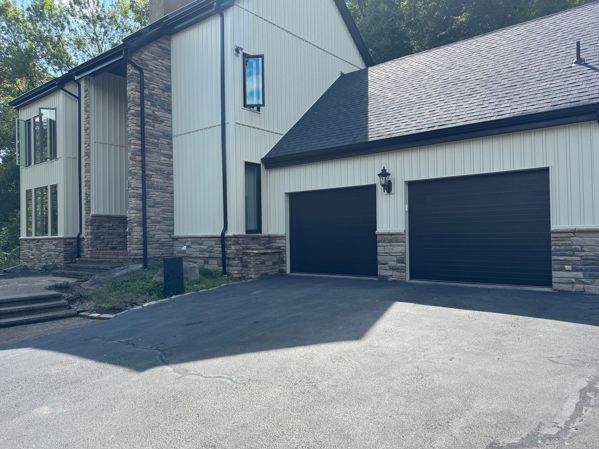 Two-story house with stone accents and a double garage under a clear sky
