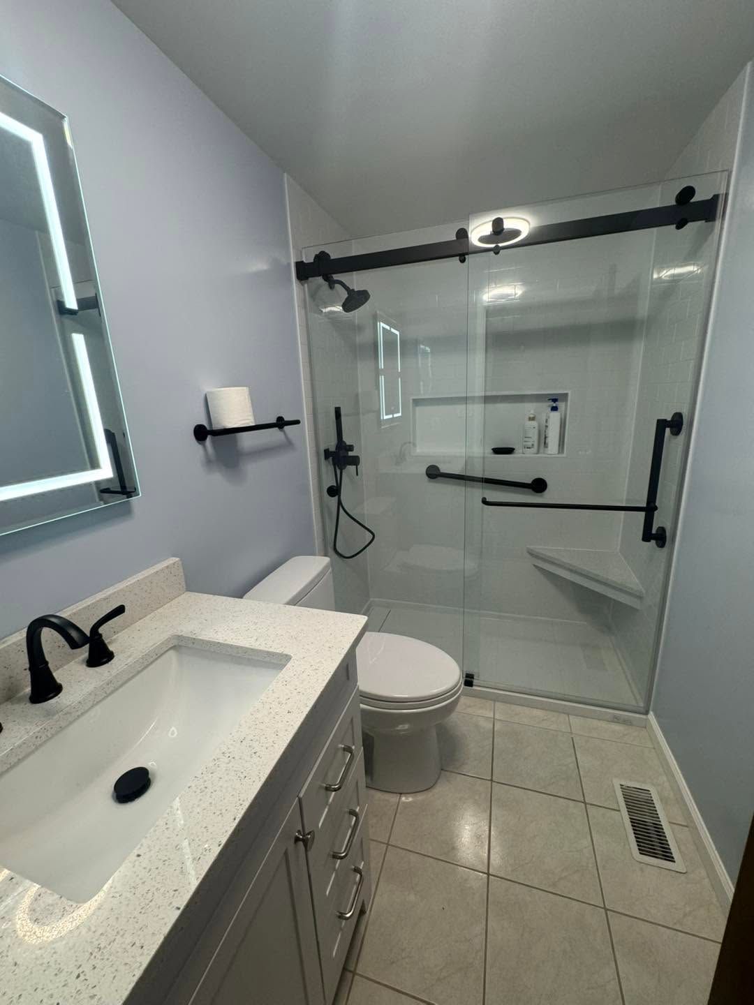 Small modern bathroom with sink, toilet, glass shower, and gray tile floor