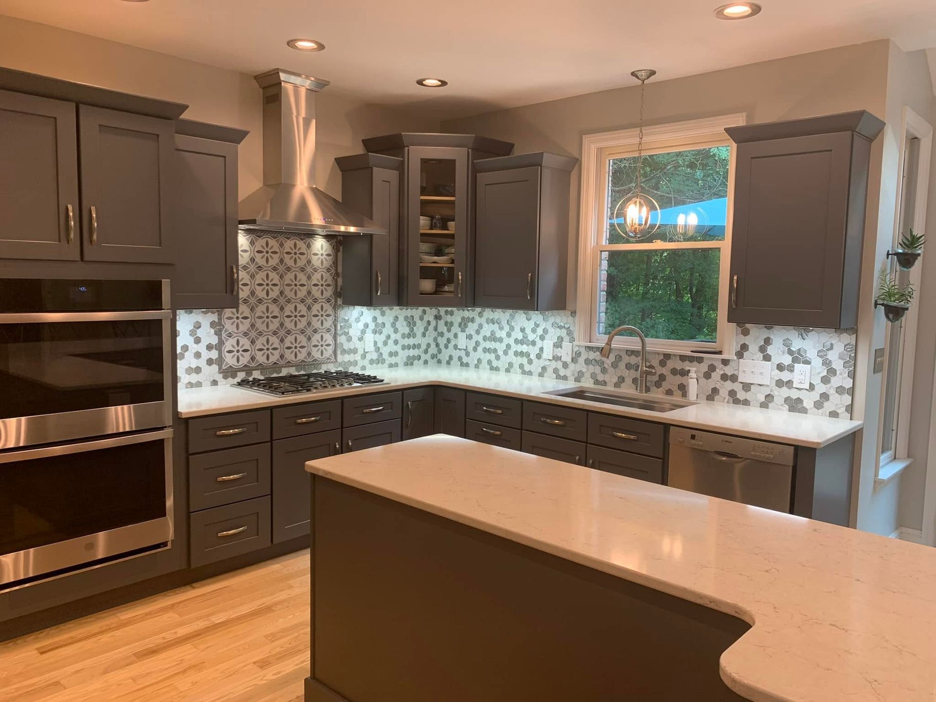 Modern kitchen with dark cabinets, mosaic tile backsplash, stainless appliances, and a large island.