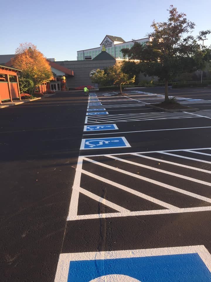 Parking lot with freshly painted handicap parking spaces; building in background.