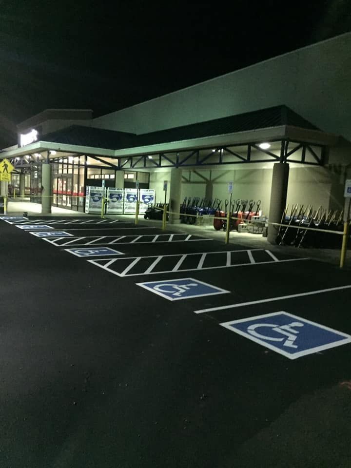 Exterior of a store with accessible parking spaces marked with blue wheelchair symbols, at night.