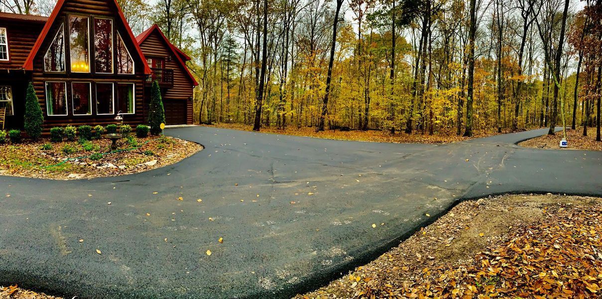 Paved driveway splitting in three directions with a house on the left and trees in the background.