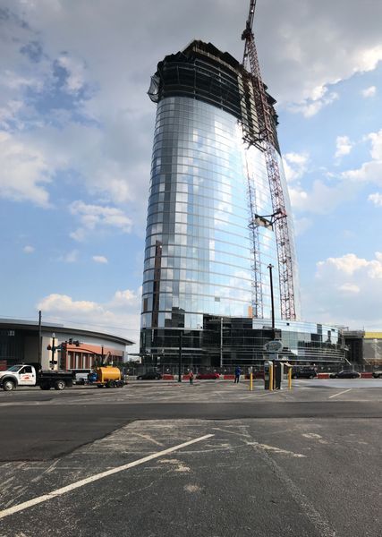 Modern glass skyscraper under construction with crane, blue sky.