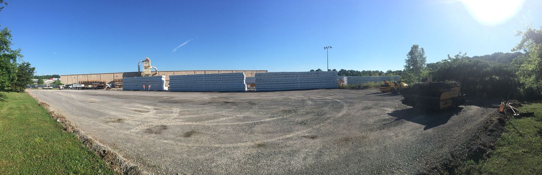 A large gravel parking area in front of a warehouse under a clear, blue sky.