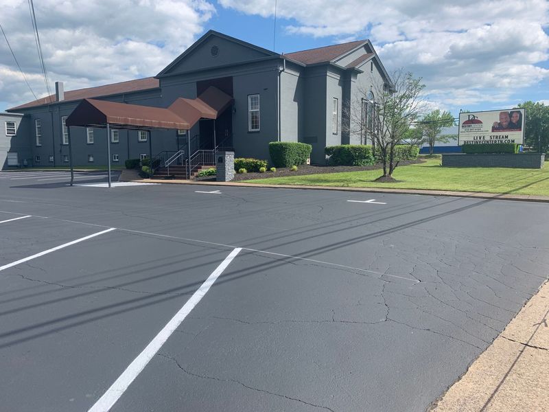 Gray church building with a parking lot on a sunny day.