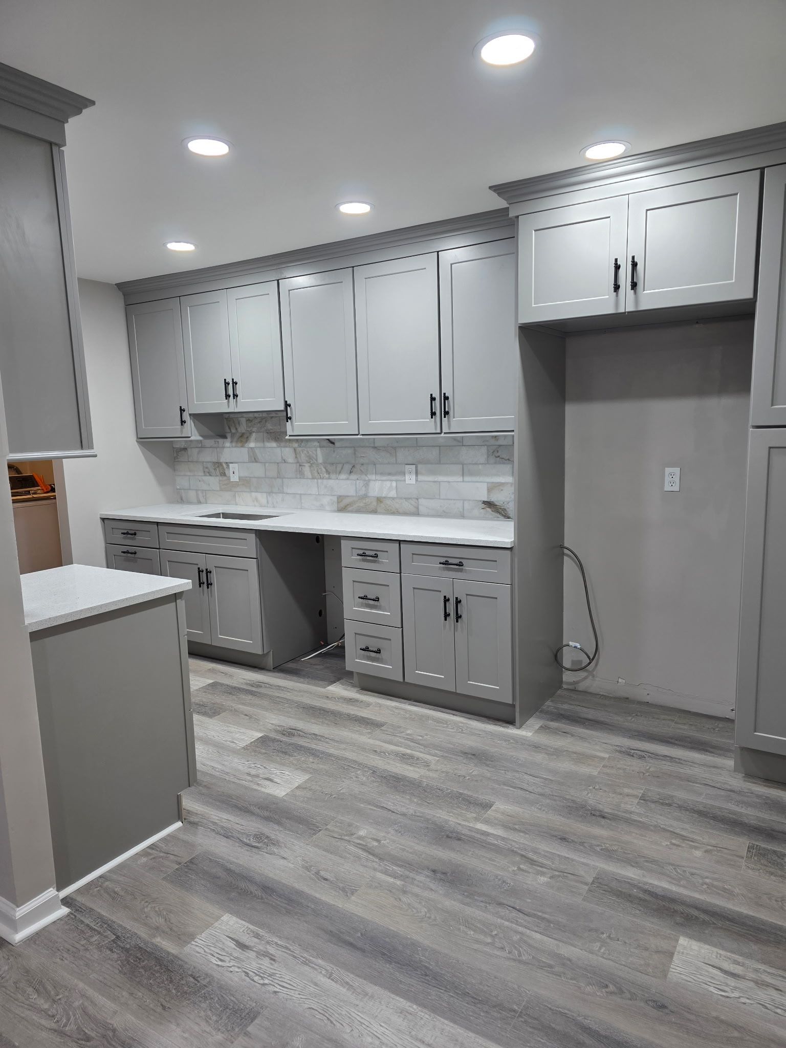 Gray kitchen with cabinets, countertops, and flooring an empty refrigerator space is visible.