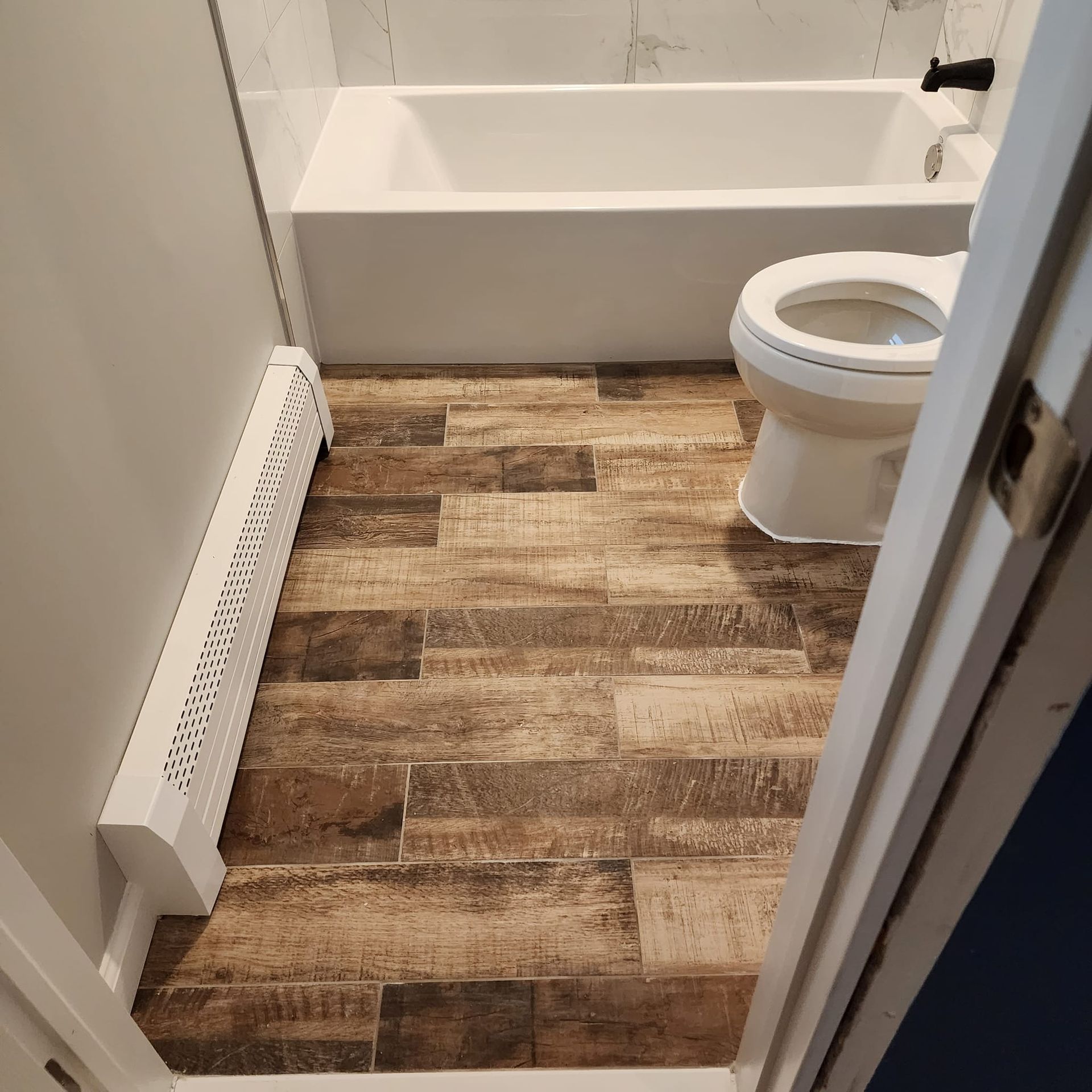 A bathroom with a toilet a bathtub and a radiator