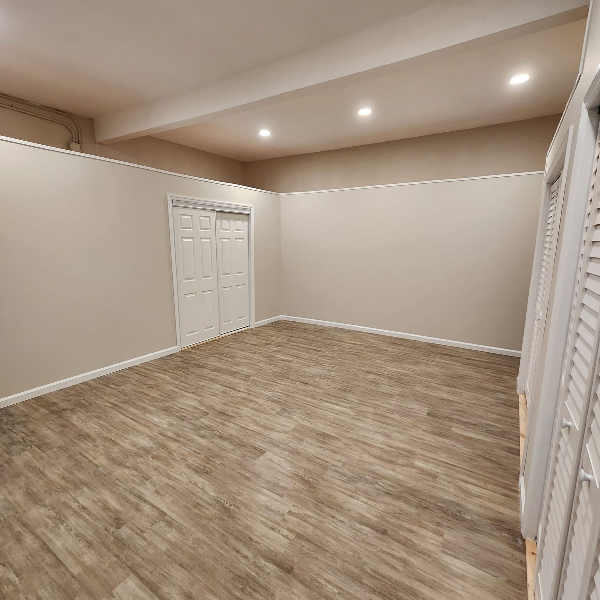 An empty room with wooden floors and white walls.