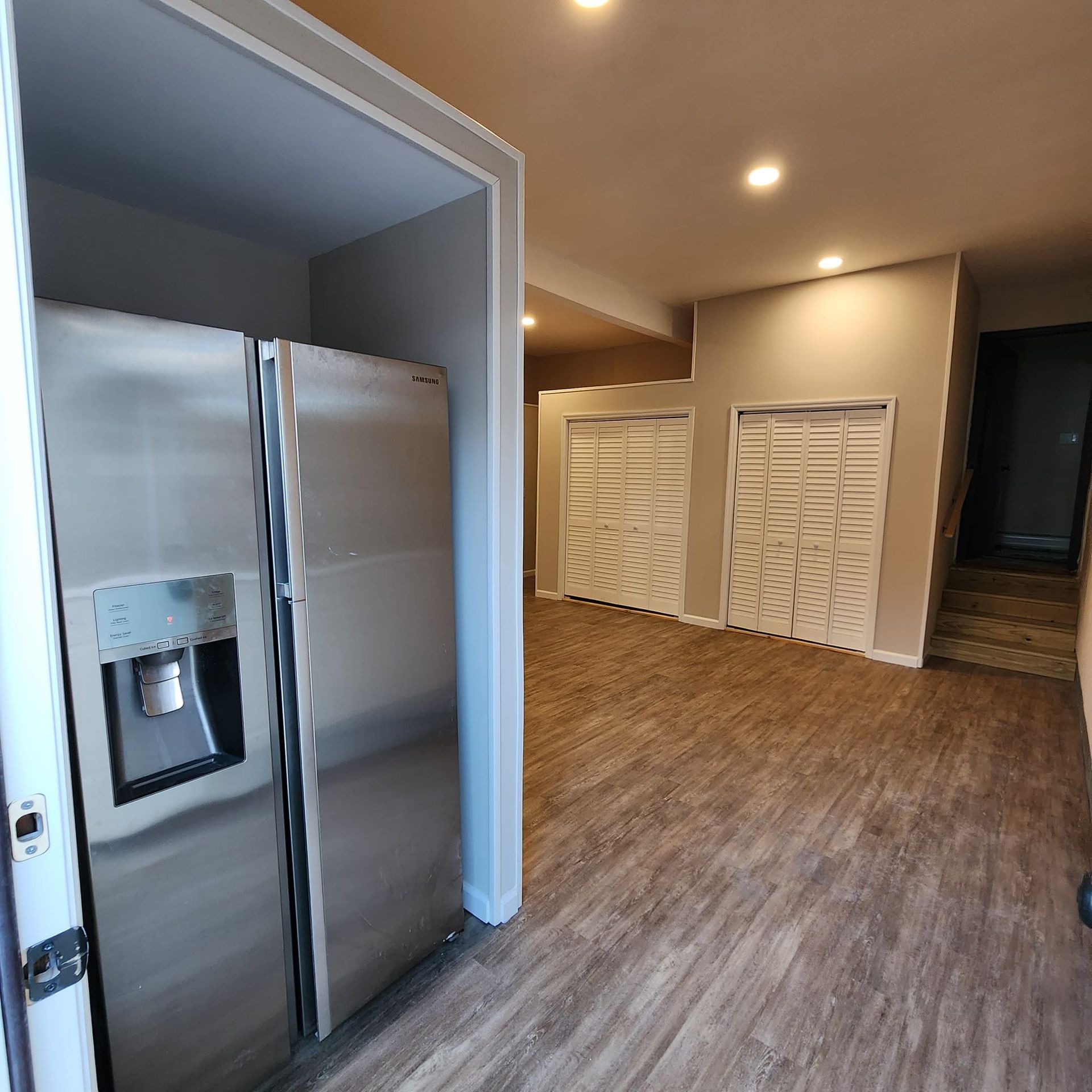 A stainless steel refrigerator is in the middle of a room.