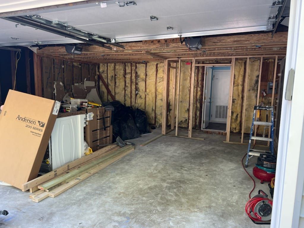 A garage is being remodeled with a ladder and a vacuum cleaner.