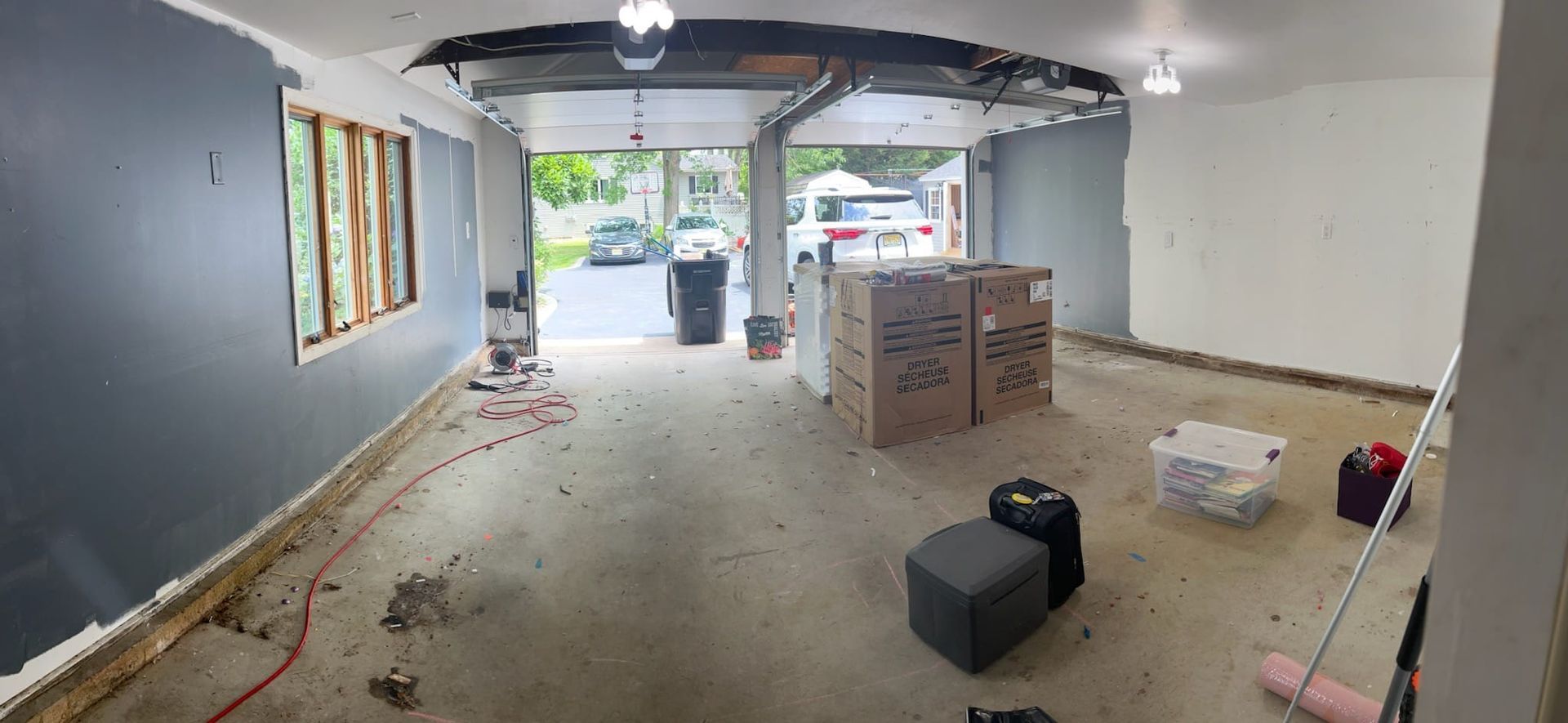 An empty garage with boxes and a broom in it.
